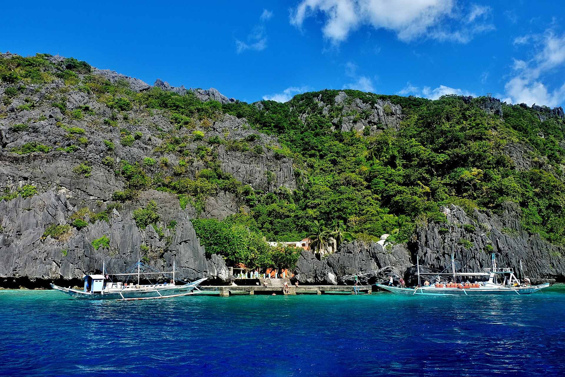 Outrigger boats at the cliff-base landing on Matinloc Island, El Nido