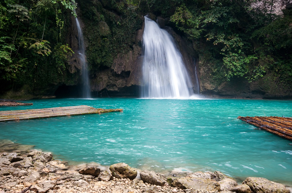 Kawasan Falls dropping into a turquoise pool with bamboo rafts